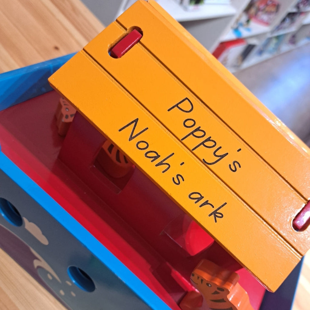 Toy set with an orange label reading 'Poppy's Noah's ark' on a wooden surface.